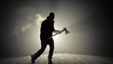 Imagem de um serial killer em uma estrada durante à noite. Ele usa roupas e touca preta e segura um machado.