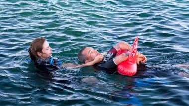 Imagem de uma mulher salvando um homem dentro da água.