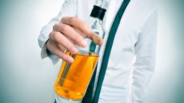 Imagem de um homem usando uma camisa social branca. Ele está segurando uma garrafa de bebida alcóolica, simbolizando uma pessoa bêbada.