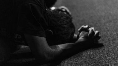 Imagem em preto e branco de um homem debruçado no chão, fazendo a sua oração.