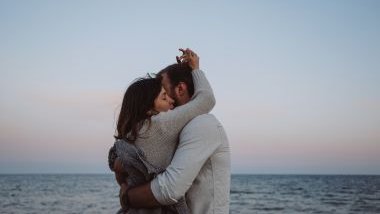 Imagem de um casal romântico se abraçando e ao fundo o mar.