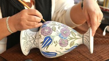 Imagem de uma mulher pintando um lindo vaso branco feito em cerâmica, simbolizando as habilidades artísticas de cada signo do zodíaco.