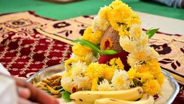 Imagem de uma tigela de prata contendo frutas, coco, canela e flores amarelas e brancas. Esses objetos formam uma oferenda.