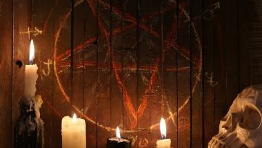 Imagem de um ritual de despacho. Velas, ossada de uma cabeça humana de plástico e um risco na parede com uma estrela na cor vemelho e amarelo complementam a foto.