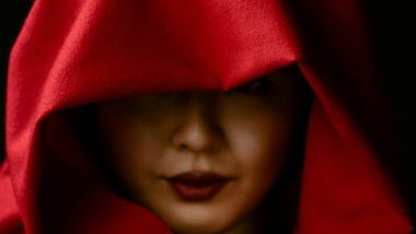 Imagem do rosto de uma mulher. Ela usa uma capa vermelha sobre a cabeça, simbolizando a pombagira Maria Mulambo.