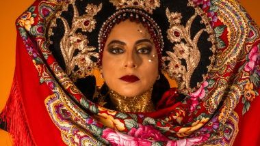 Imagem do rosto de uma mulher todo pintado e adornado com pedras, lenços e arranjos dourados e vermelhos, simbolizando a cigana Carmencita da Umbanda.