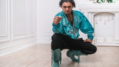 Imagem de um homem cigano, usando uma linda camisa na cor azul claro, com bordados nas cores dourado e prata, uma calça preta e uma bota também na cor azul. Ele simboliza o cigano Igor.