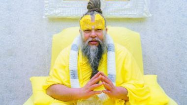 Imagem de um homem usando uma roupa amarela, sentando em uma cadeira. Ele tem um coque com uma trança grande, além de barba e bigode. Ele está simbolizando um líder espiritual, o babalorixá do Candomblé.