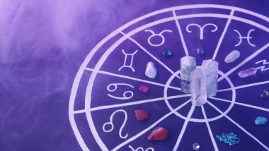 No foco da imagem, há uma Roda do Zodíaco com os símbolos dos signos e há cristais em cima dela.