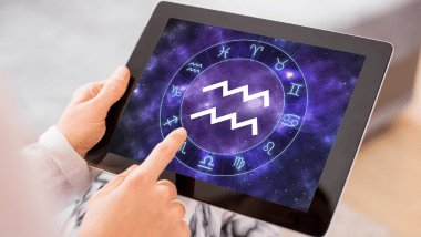 Pessoa usando tablet com símbolo de Aquário exibido em um círculo zodiacal na tela.