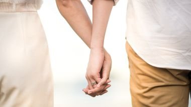 Imagem de um casal de costas e de mãos dadas.