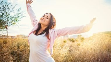Imagem de uma mulher feliz no meio de um lindo campo.