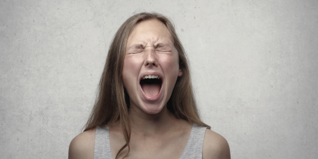 Mulher chora com os olhos fechados e grita.