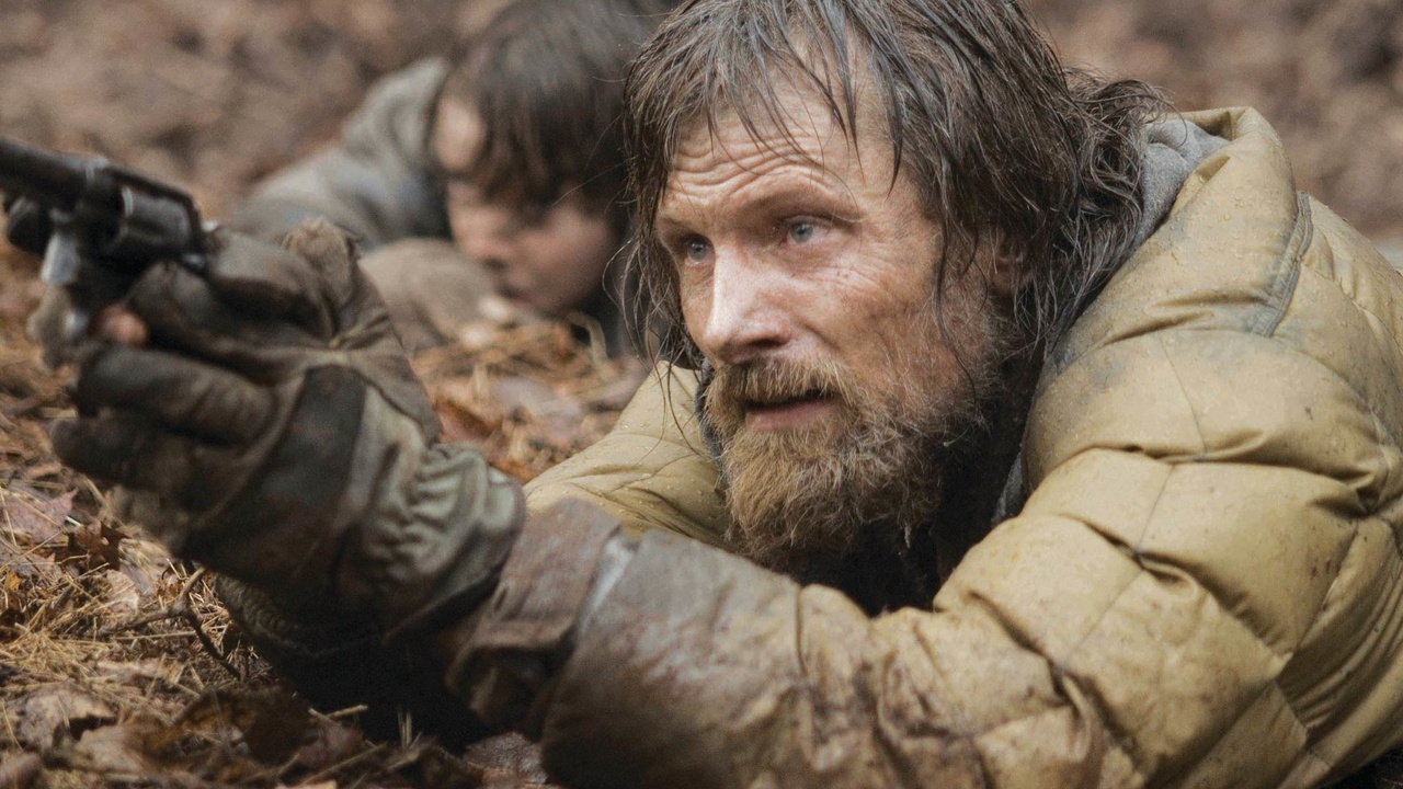 Homem deitado no chão segurando uma arma