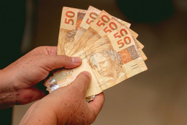 Pessoa segurando notas de cinquenta reais