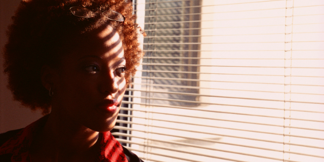 Mulher olhando pensativa para a janela