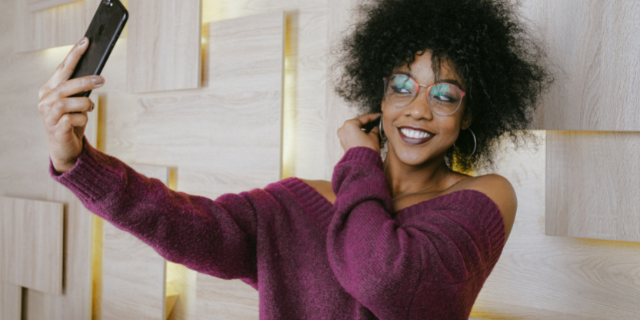 Mulher de óculos sorrindo tirando selfie