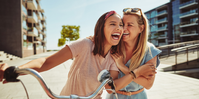 Amigas sorrindo e andando de bicicleta juntas