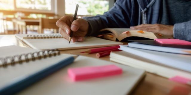 Homem organizado escrevendo no seu bloco de caderno