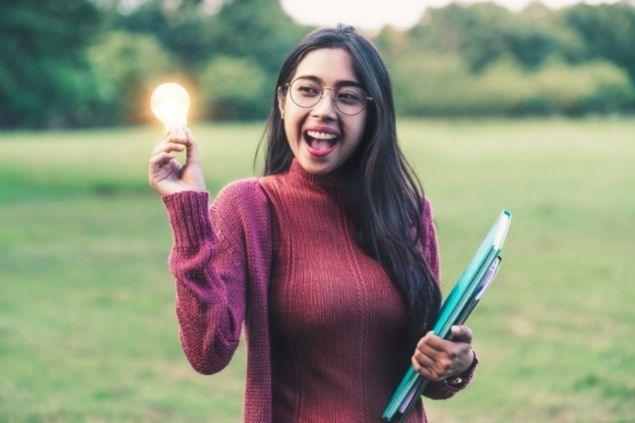 Mulher sorridente segurando lâmpada acesa na mão