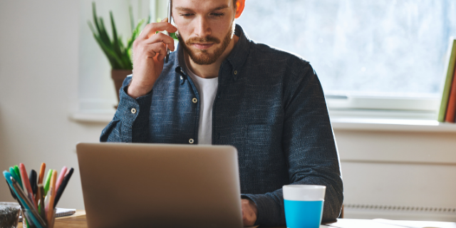Homem concentrado trabalhando enquanto falava no telefone