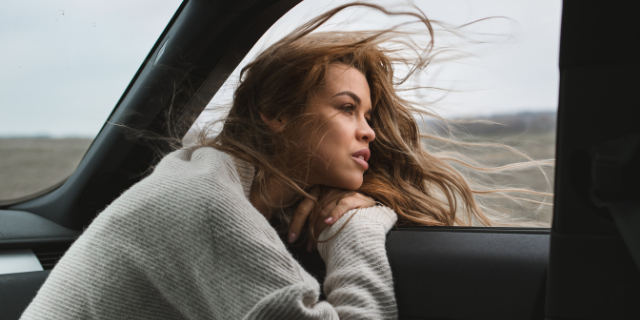 Mulher pensativa olhando pela janela do carro