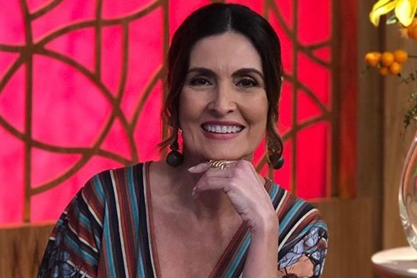 Jornalista Fátima Bernardes com mão levada ao queixo e expressão sorridente