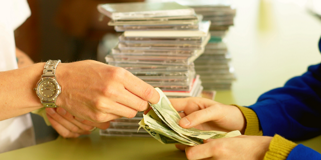 Homem na bancada pagando por pilhas de CD