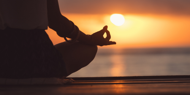 Mulher meditando sob o pôr do sol