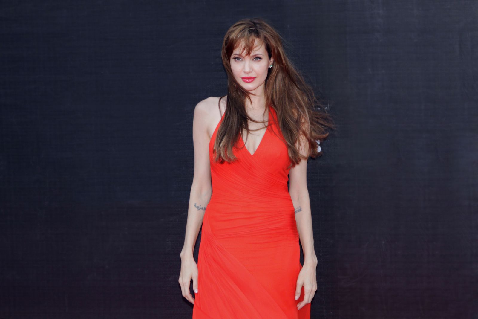 Angelina Jolie usando vestido com cabelo comprido ao vento