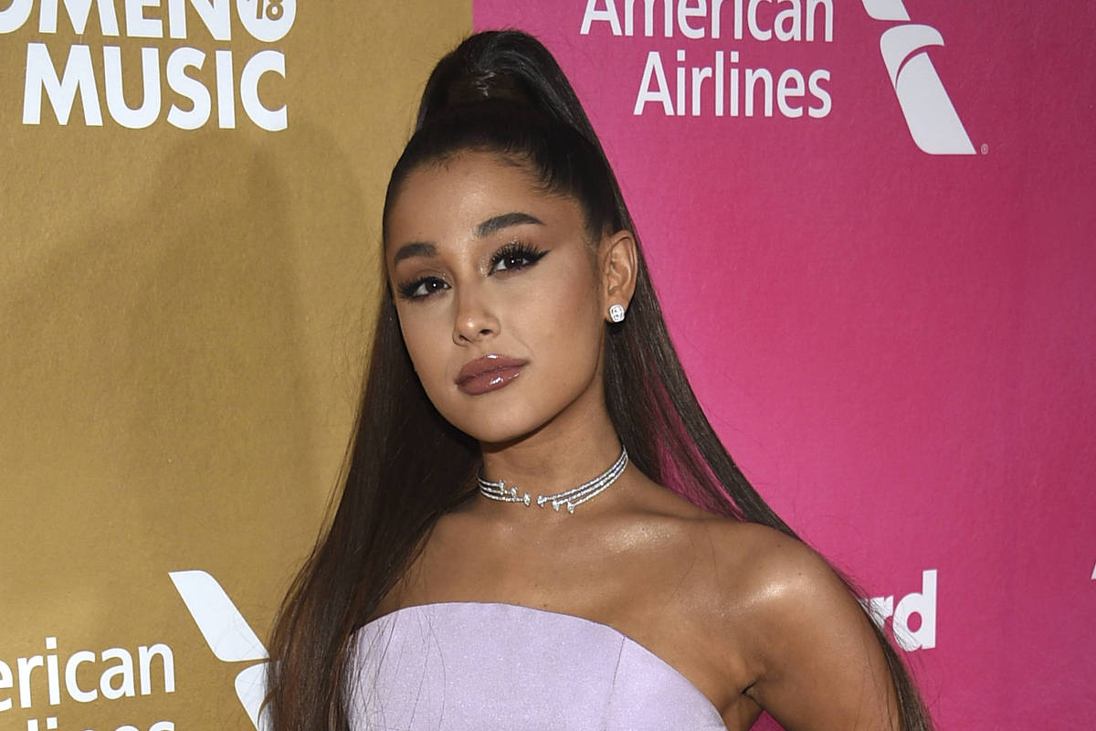 Ariana Grande posando para foto em entrada de evento, usando seu famoso rabo de cavalo 