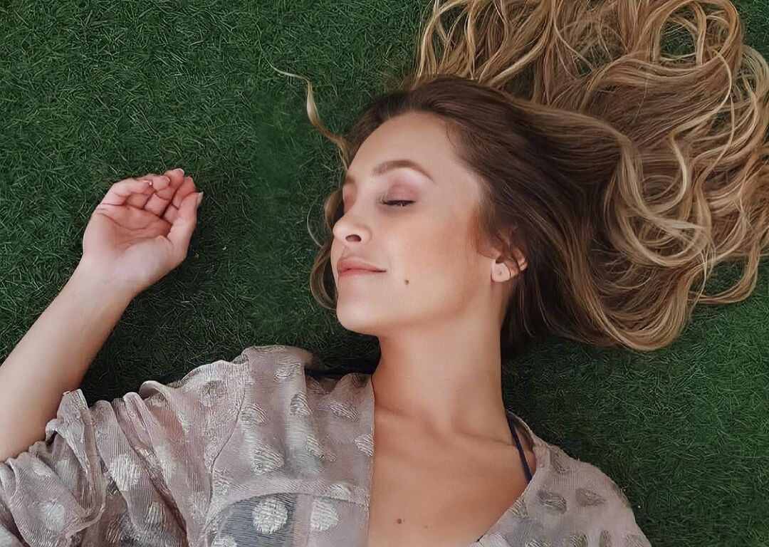 Atriz Carla Diaz deitada na grama.