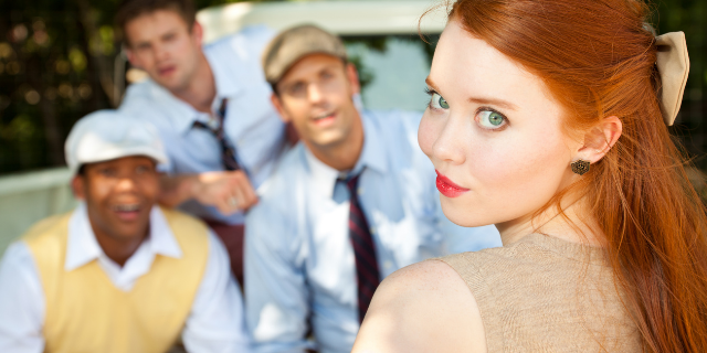 Mulher sorrindo para a câmera com 3 homens olhando para ela