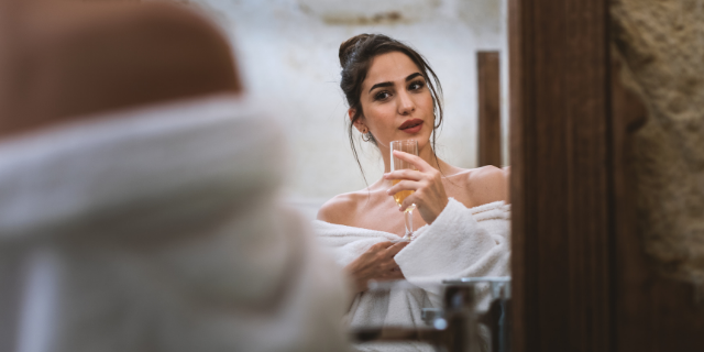 Mulher tomando champanhe olhando para seu reflexo no espelho