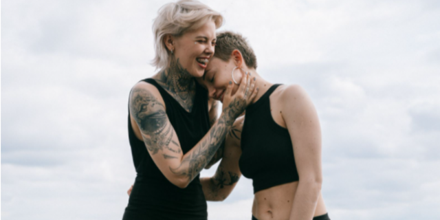 Mulher apoiando sua cabeça do ombro de outra mulher que está sorrindo