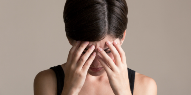 Mulher estressada com as mãos sob o rosto