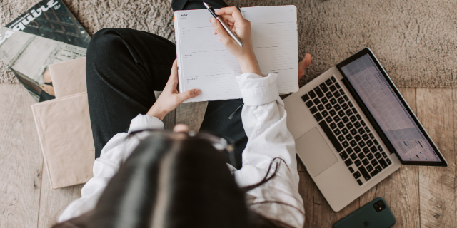 Jornalista escrevendo em agenda sentada no chão