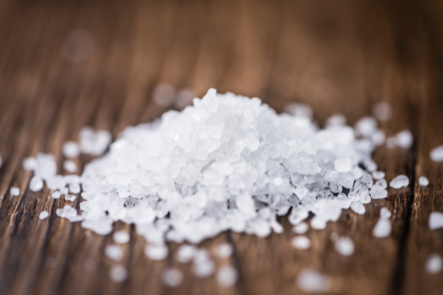 sal grosso espalhado em cima de uma mesa de madeira