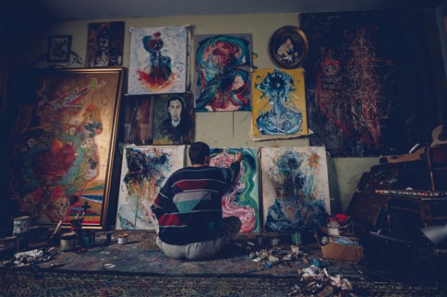 homem sentado no chão pintando quadros