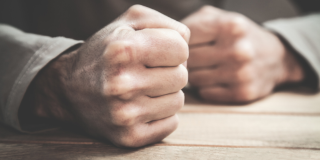Mãos de pessoa com os punhos fechados de raiva