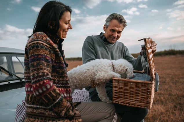 Mulher presenteando homem com uma cesta de piquenique com comida