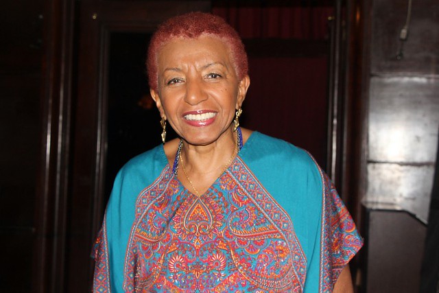 Mulher negra de cabelos curtos e ruivos e expressão sorridente.