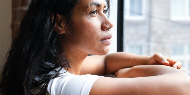 Mulher olhando pensativa para a janela
