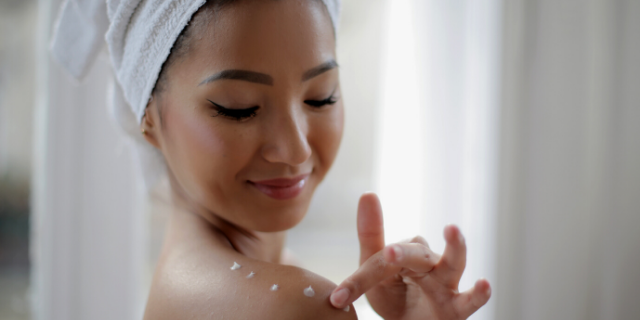 Mulher passando creme corporal no ombro