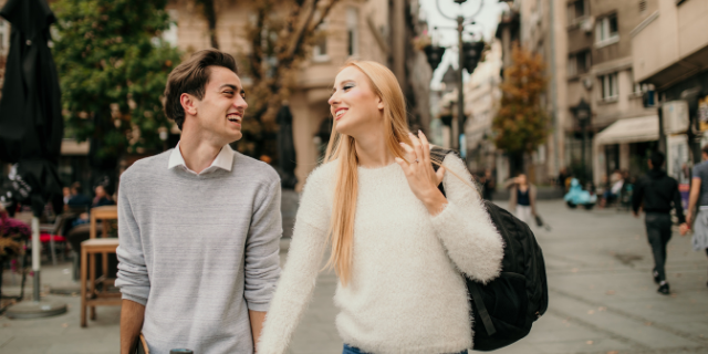 Casal sorrindo caminhando juntos e mãos dadas