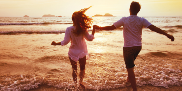 Casal correndo para o mar de mãos dadas juntos