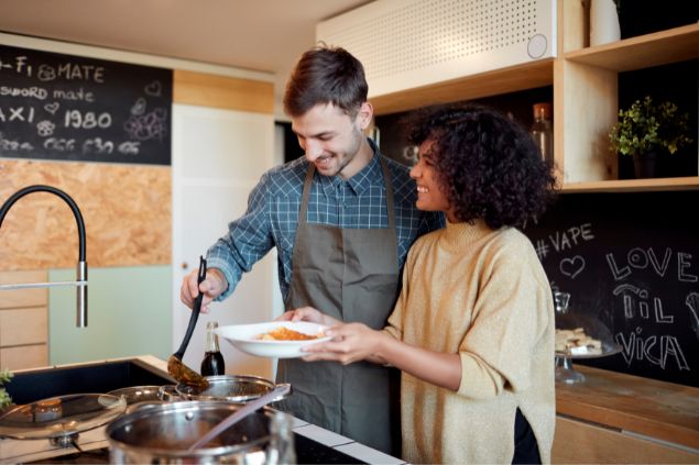 casal sorridente cozinhando juntos