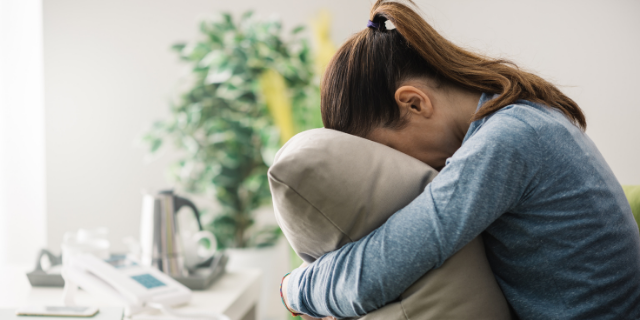 Mulher estressada com o rosto debruçado no travesseiro