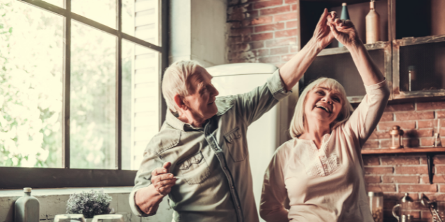 Casal idoso feliz e dançando na cozinha