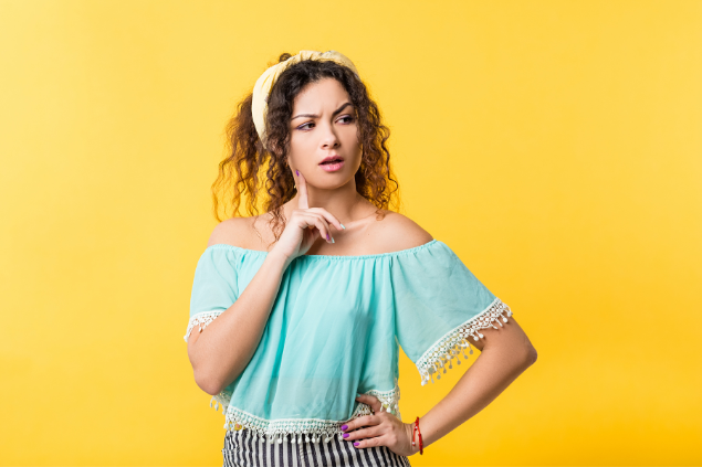 Mulher branca com expressão de curiosa, com mão no rosto